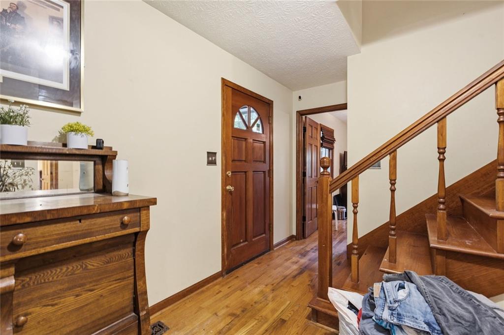 Entry foyer with a wooden front door, hardwood floors, and a wooden staircase.