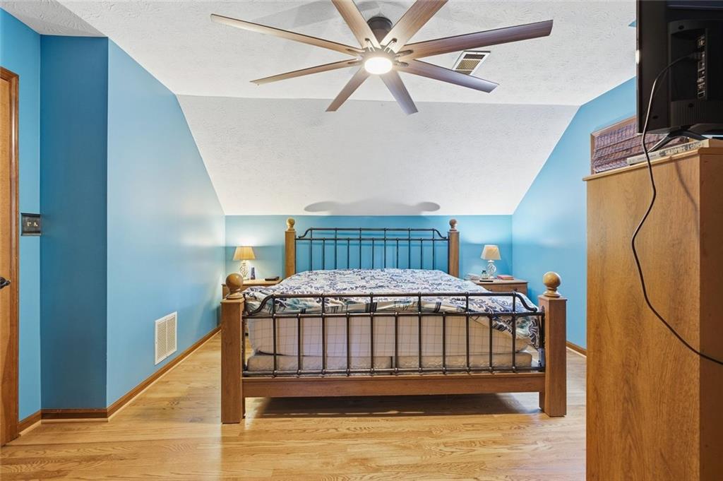 Bedroom with blue walls, a metal-and-wood bed, hardwood floors, and a ceiling fan.