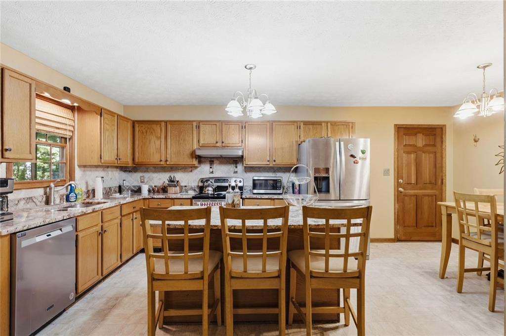 Kitchen with wood cabinetry, granite counters, stainless steel appliances, and a large island with seating.