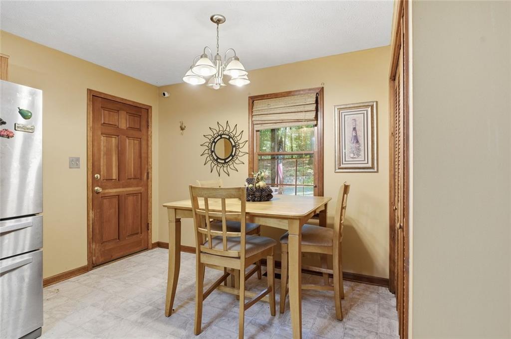 Dining area with a wooden table and chairs beside a window and stainless steel refrigerator.