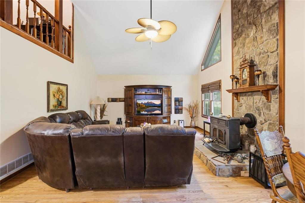 Living room with leather sectional, vaulted ceiling, and stone fireplace with wood-burning stove.