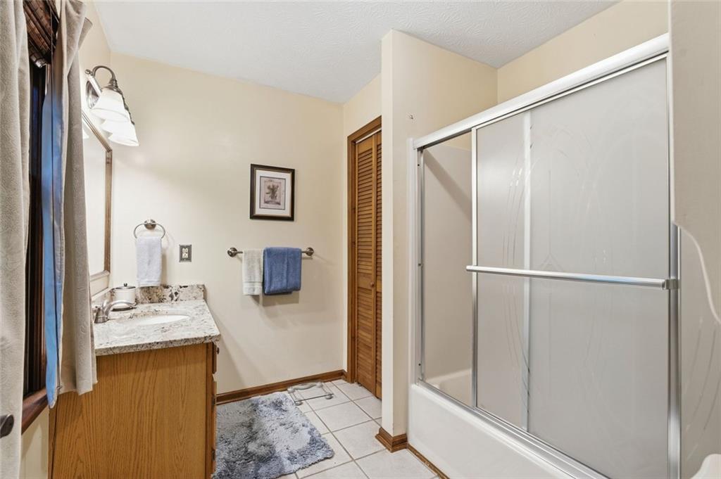 Bathroom with a granite-topped wood vanity and a tub-shower with sliding glass doors.
