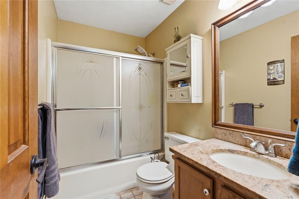 Bathroom with frosted sliding shower doors, a wood vanity, and a large framed mirror.