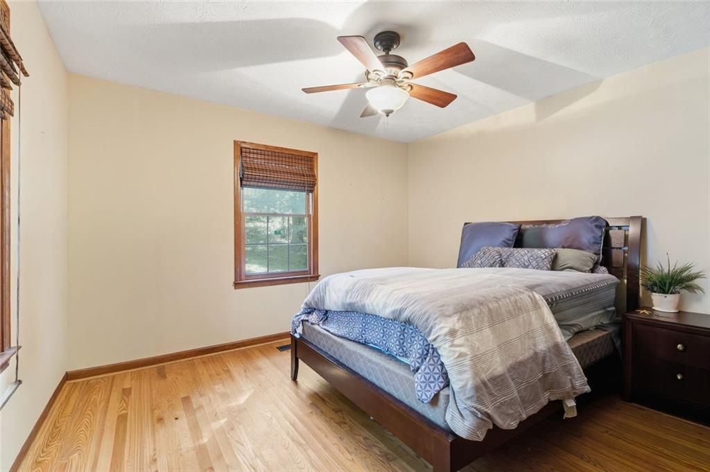 Bedroom with a dark wood bed, hardwood floors, and a ceiling fan with light.