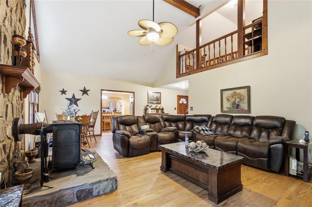Living room with a stone fireplace, leather sectional, vaulted ceiling and loft railing.