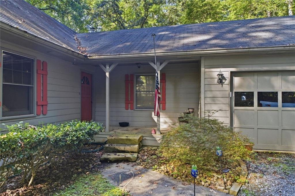 Gray house with red shutters and door, covered entry, and attached garage.