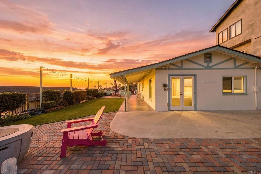 Coastal home patio with a red Adirondack chair and ocean view at sunset.