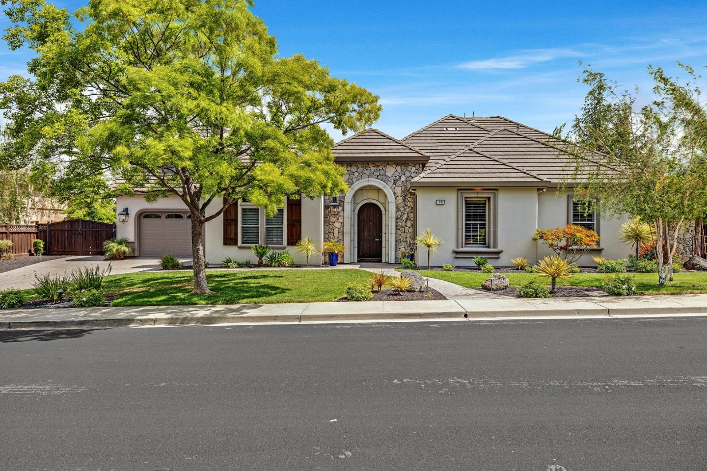 Single-story home with a stone-accented entry, arched front door, tile roof, and landscaped yard.