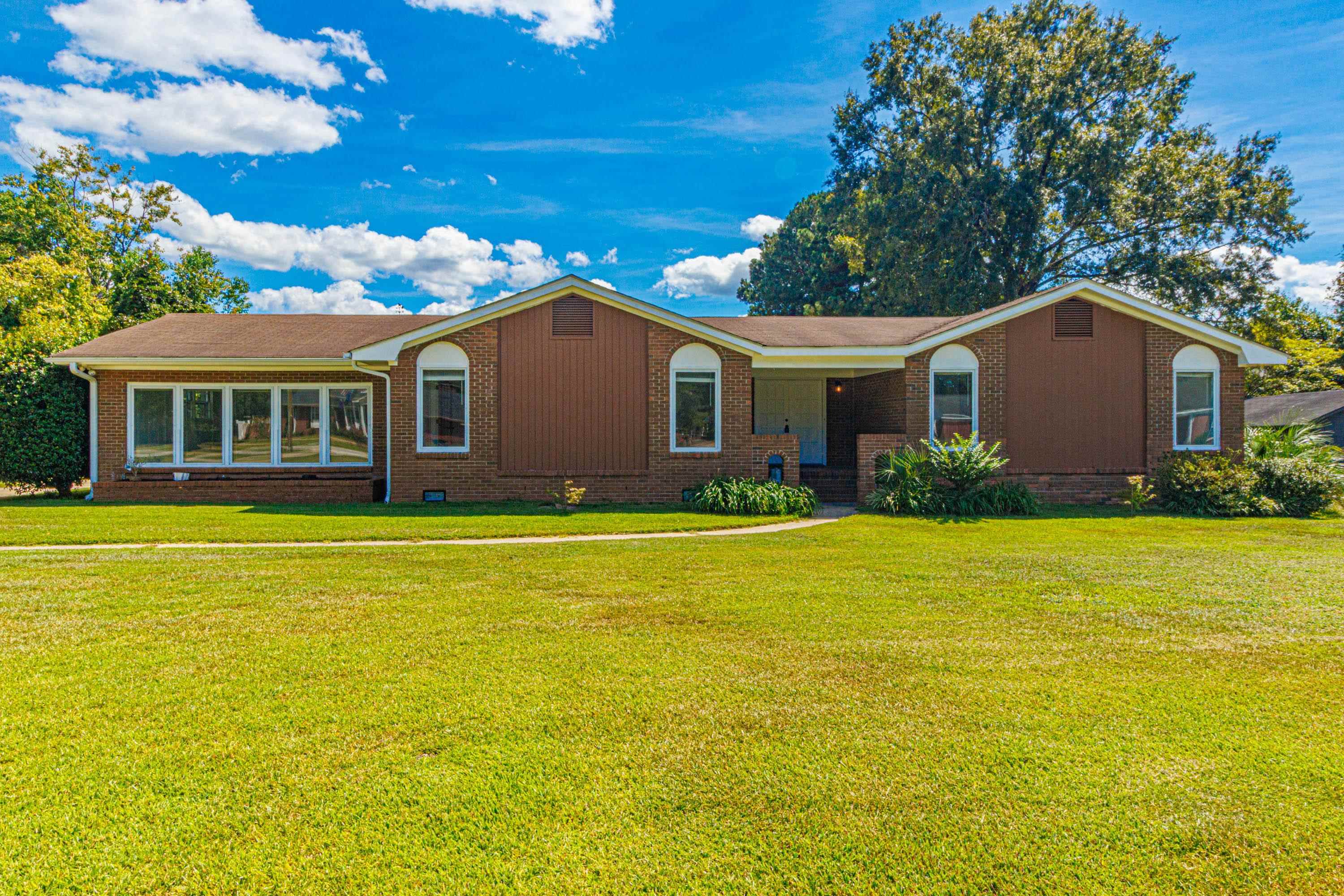 Single-story brick house with brown siding, a recessed entrance, and a wide green lawn.