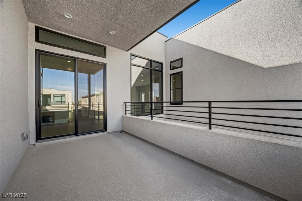 Covered balcony with black railing and large sliding glass doors.