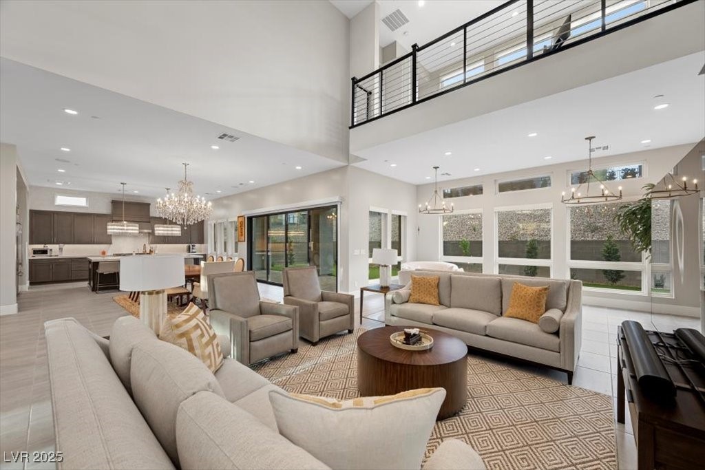 Open-plan great room with vaulted ceiling, beige seating, dark-cabinet kitchen, and large windows.