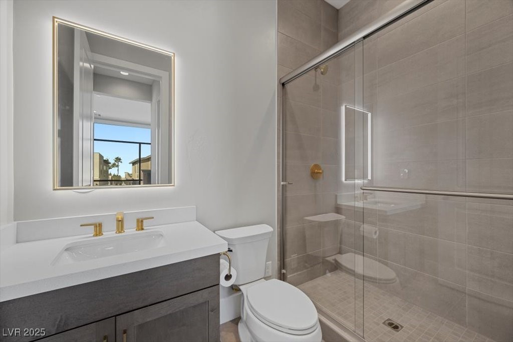Modern bathroom with a gold-faucet vanity and glass-enclosed tiled shower.