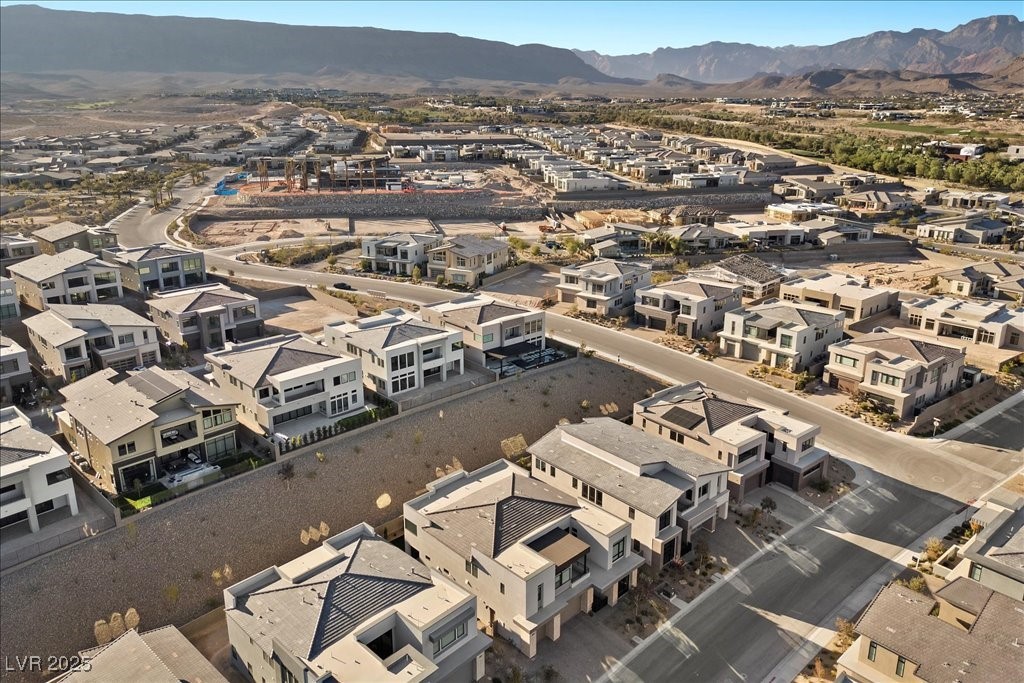 Aerial view of modern homes and a construction site with mountains in the distance.