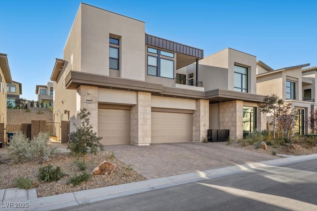 Modern two-story home with two garage doors, large windows, and desert landscaping.