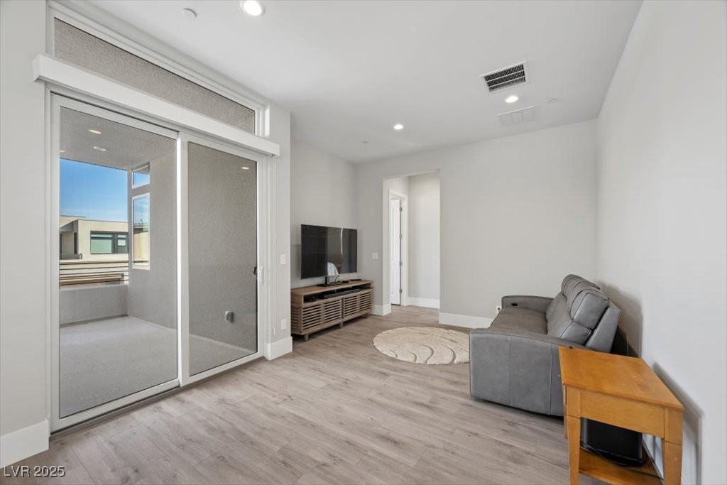 Living room with gray sofa, television, wood-look flooring, and sliding glass doors to a balcony.