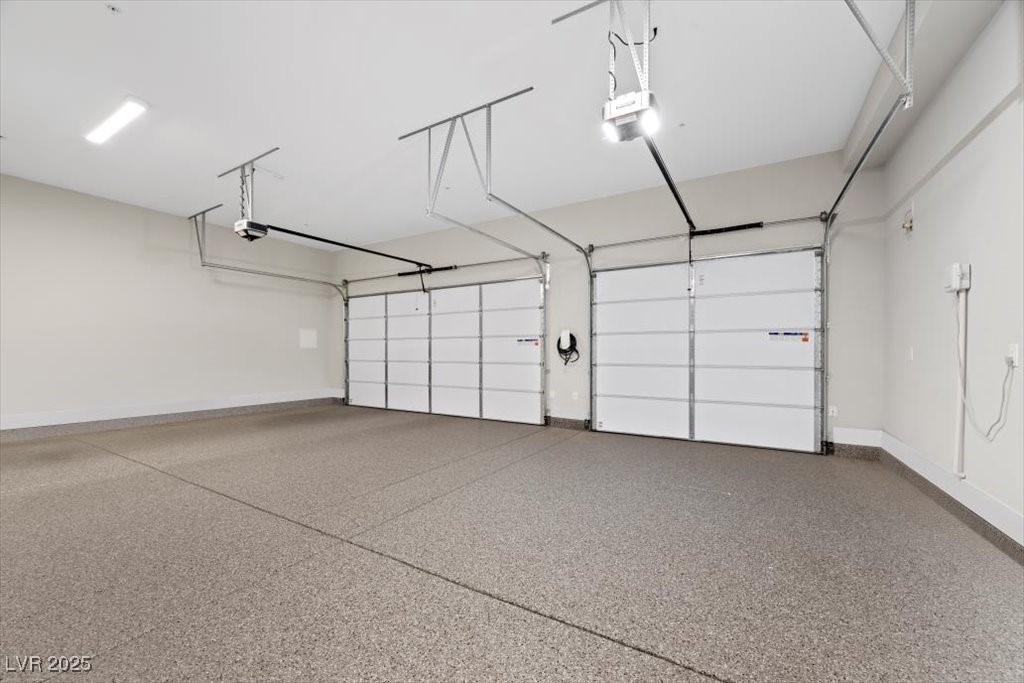Vacant garage with two overhead doors and a speckled epoxy floor.