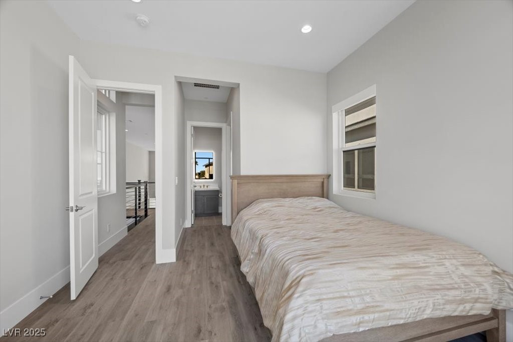 Bedroom with a wood-framed bed, gray wood-look flooring, and an adjoining bathroom vanity.