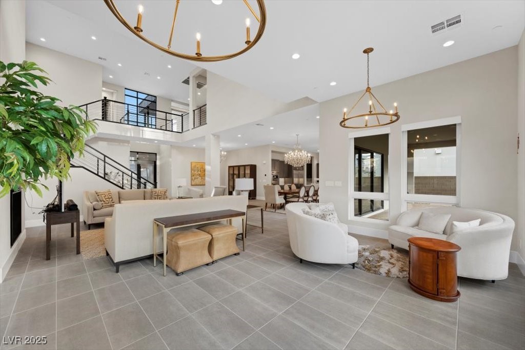Two-story living room with white seating, gray tile floors, and a black-railed staircase.