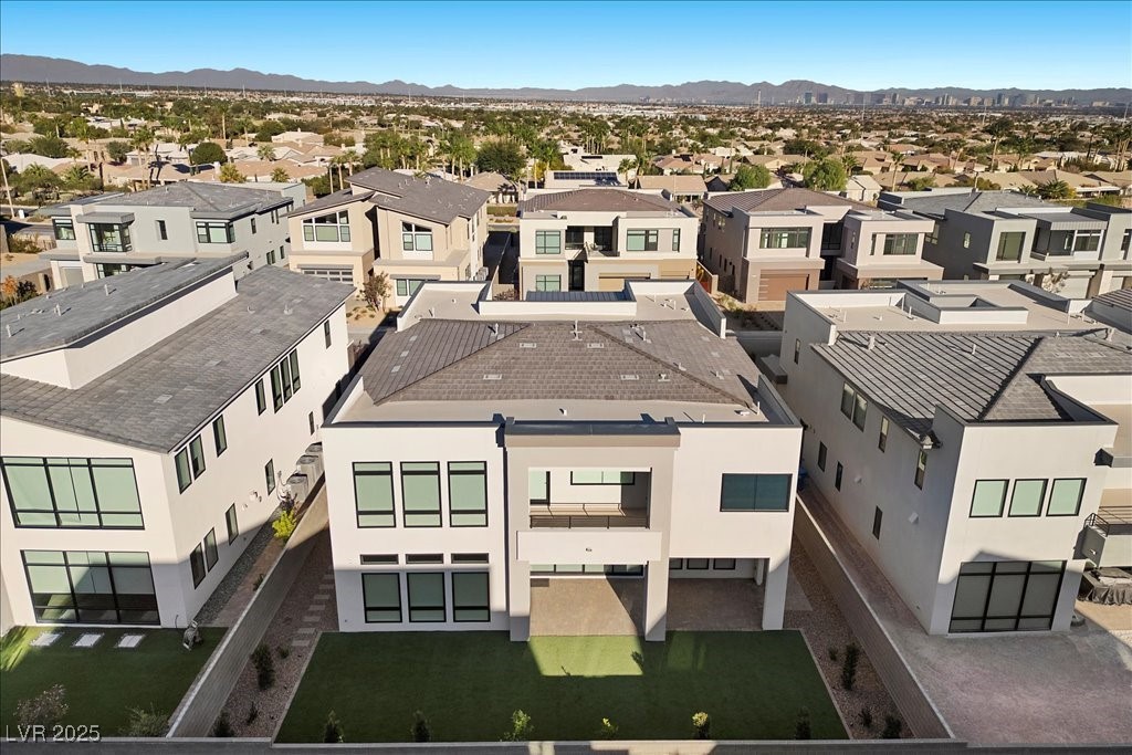 Aerial view of a modern two-story home with a small lawn, surrounded by neighboring houses.
