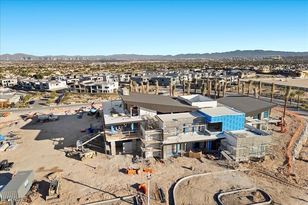 Aerial view of a modern home under construction, with angular roofs and Las Vegas Valley mountains beyond.