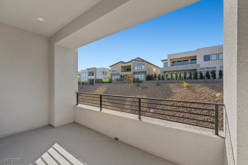 Covered patio with black railing overlooking modern neighboring homes.