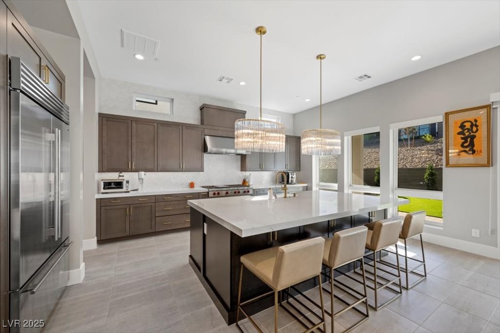 Modern kitchen with a large white island, bar seating, stainless appliances, and two pendant lights.