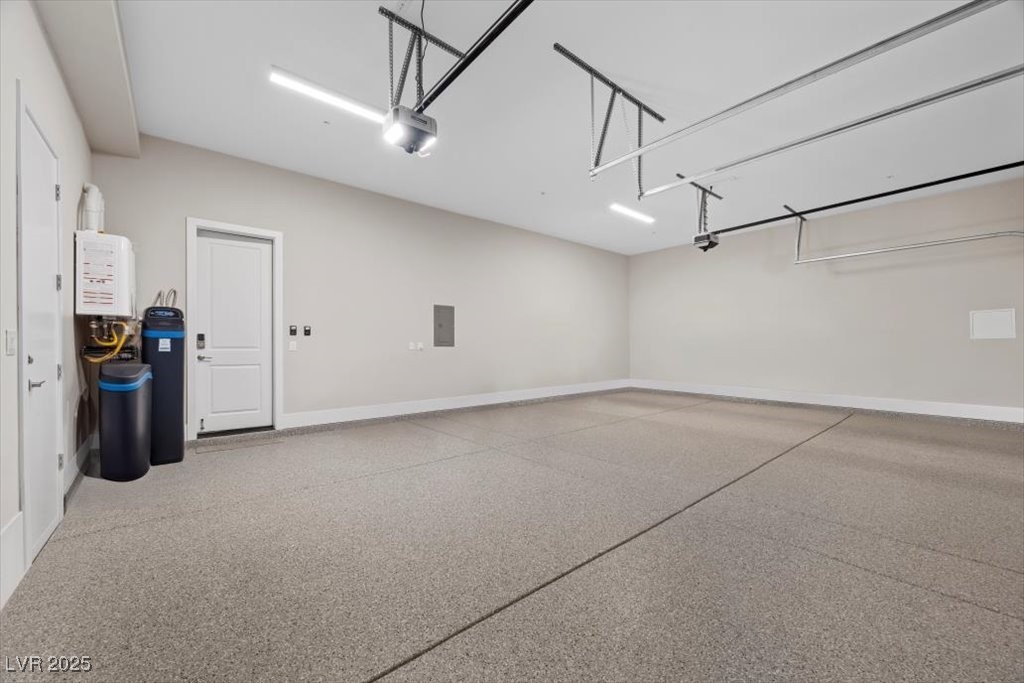 Empty garage with a speckled epoxy floor, overhead door tracks, and utility equipment.