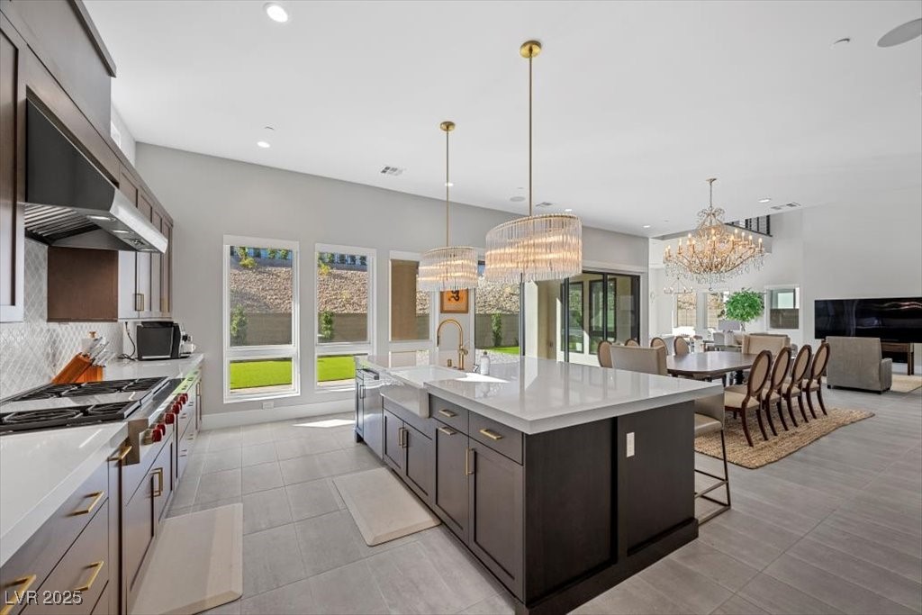 Open kitchen with a large quartz island, dark cabinetry, and a dining area beneath a chandelier.