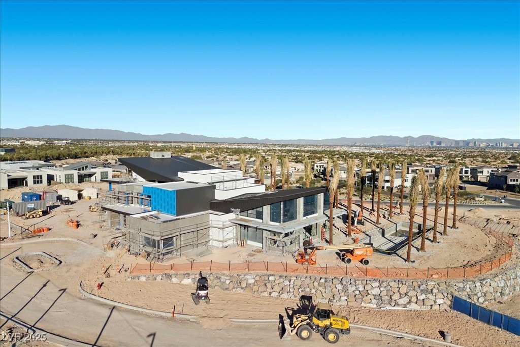 Modern home under construction, with tall palms and the Las Vegas Valley in the distance.