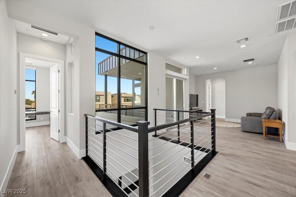 Upstairs living area with an open stairwell, large windows, and a gray sofa.