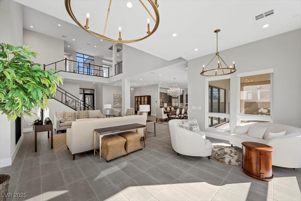 Furnished living room with a high ceiling, black-railed staircase, and open dining area.