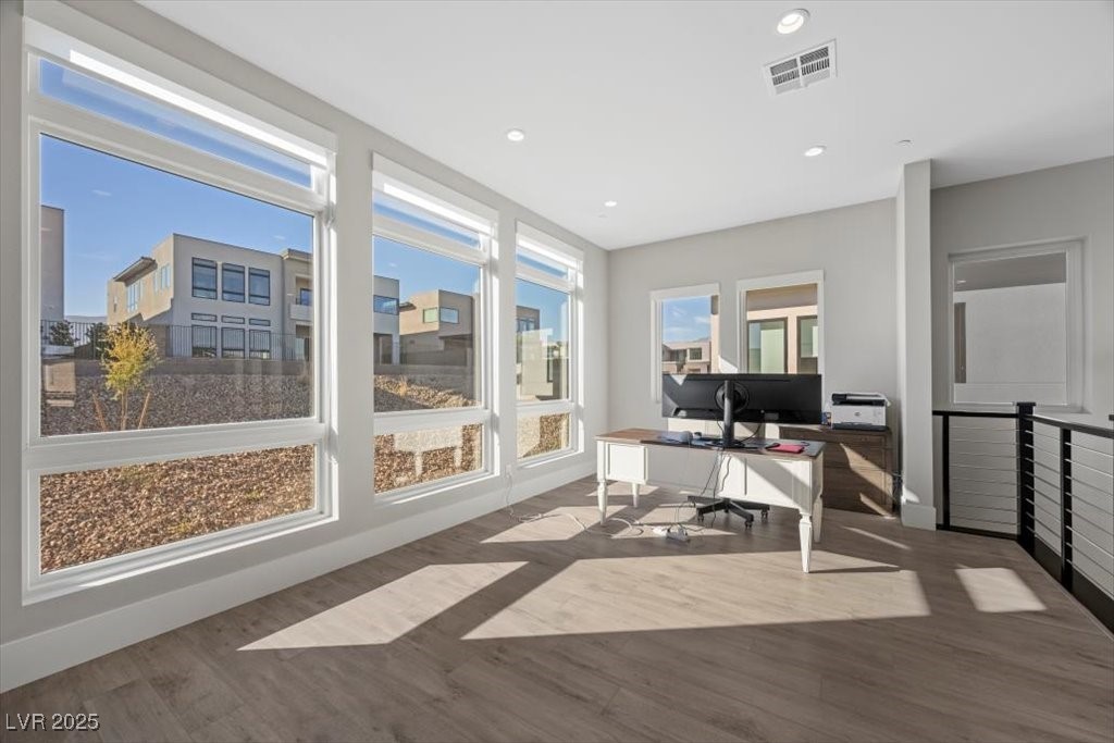 Bright upstairs office with large windows, a computer desk, and views of neighboring homes.