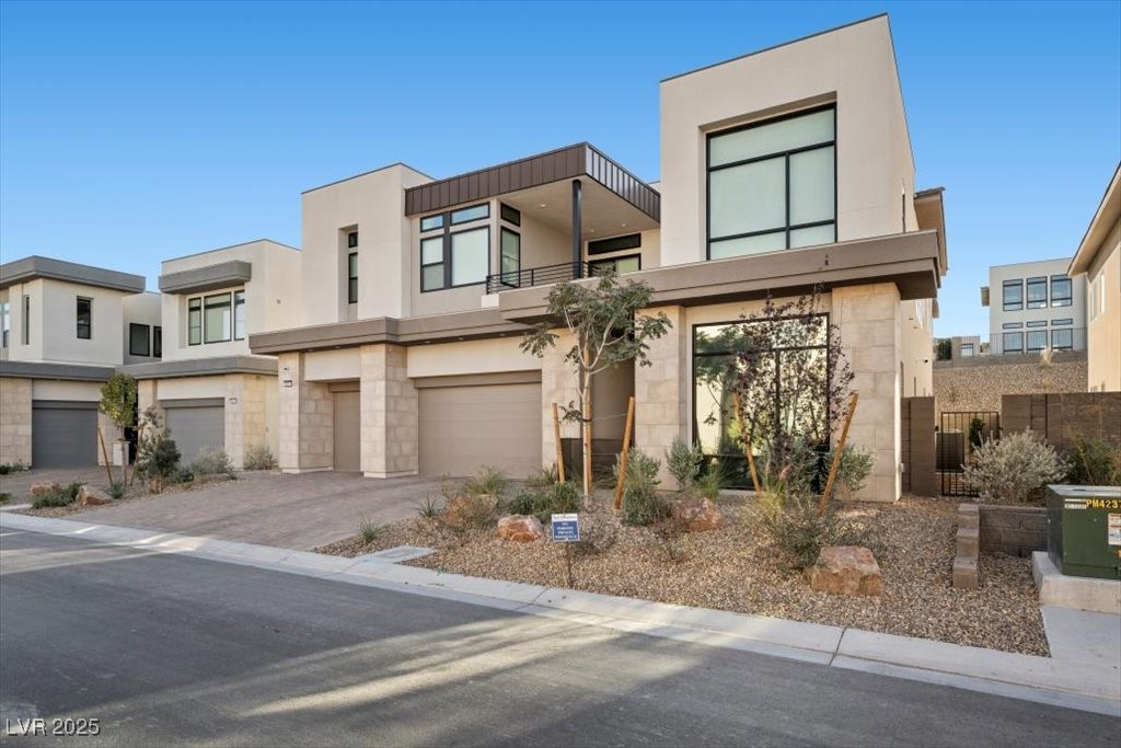 Modern two-story Las Vegas home with large windows, three garage doors, and desert landscaping.