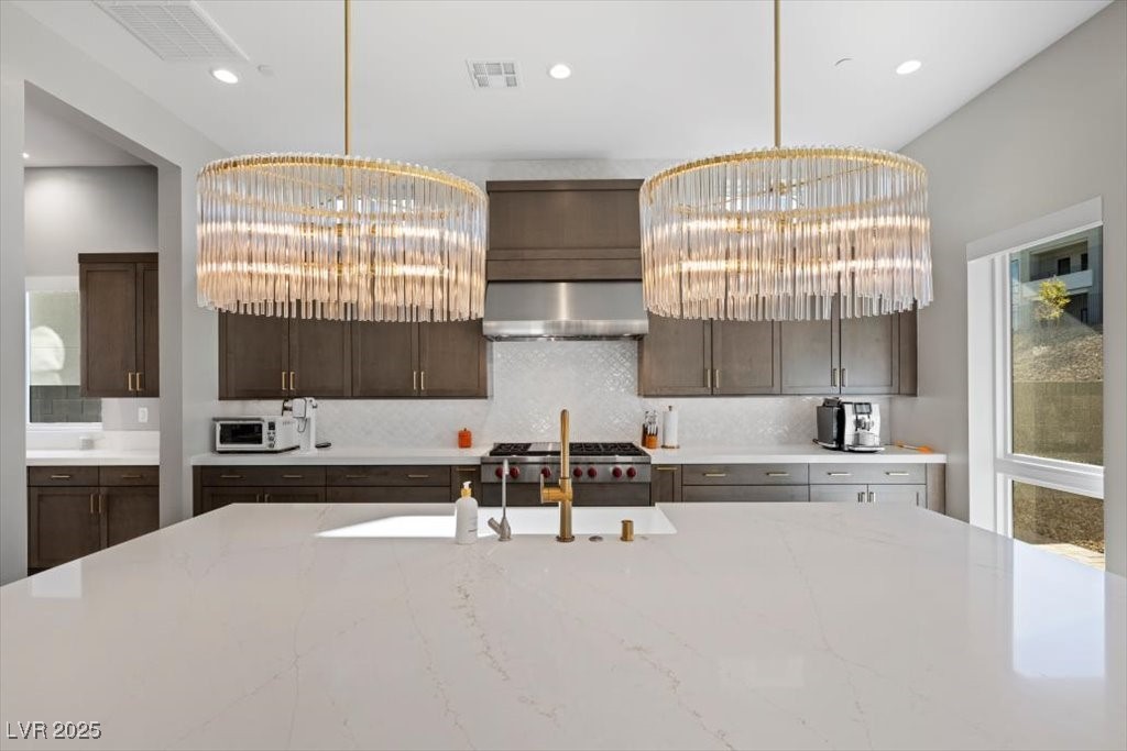 Contemporary kitchen with a large white stone island, dark wood cabinetry, and two crystal pendant lights.