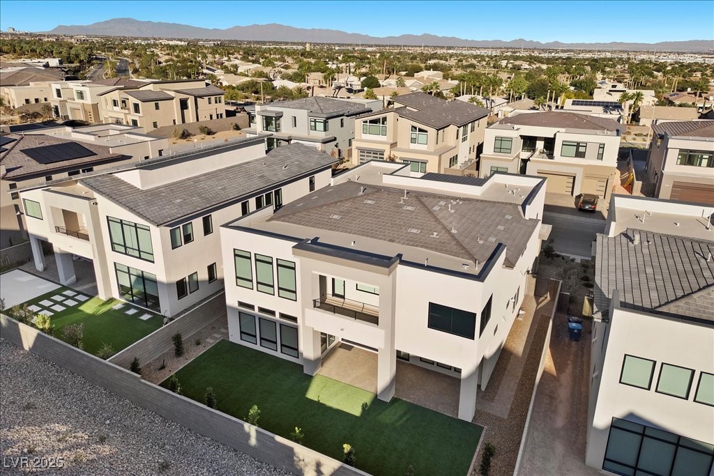 Modern two-story white home with a gray roof and green lawn, viewed from above among neighboring homes.