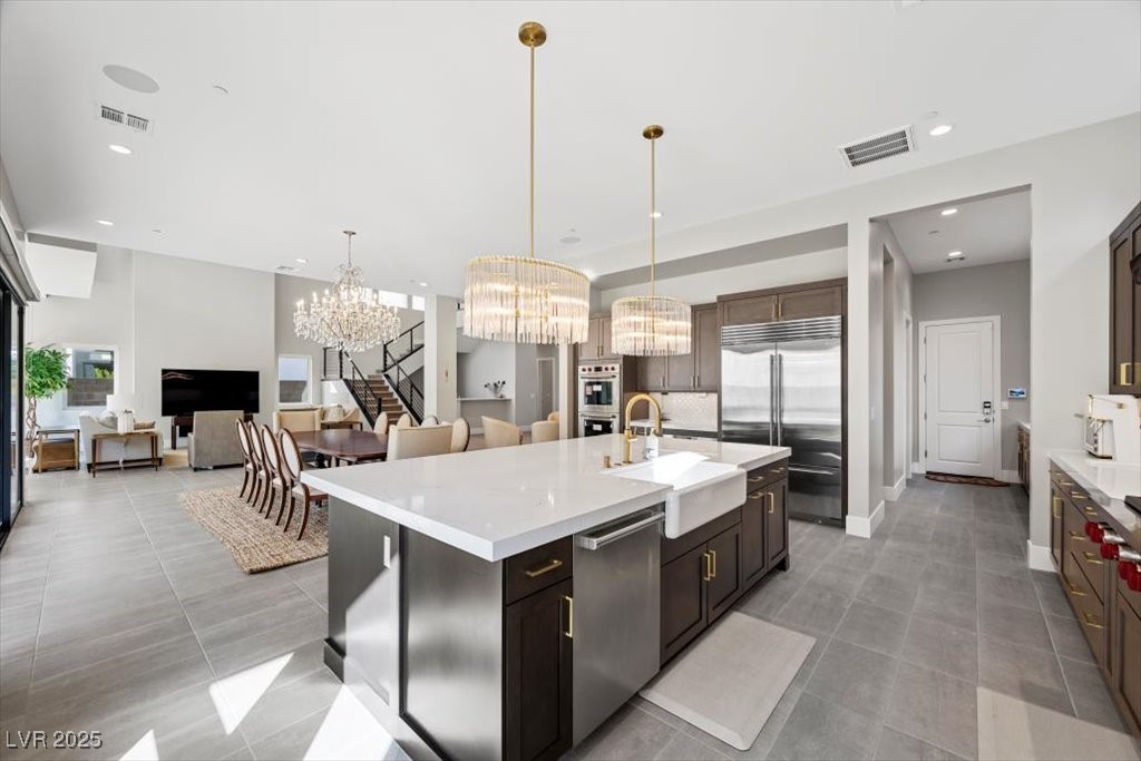Open-plan kitchen with a large white island, dark cabinets, and stainless steel appliances.
