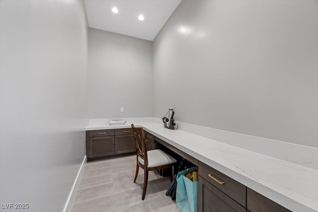 Built-in workspace with a long white counter, dark cabinets, and a wooden chair.