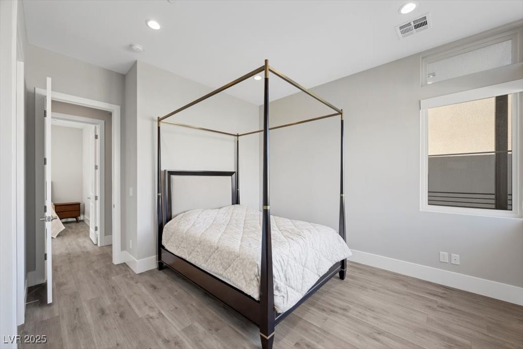 Bedroom with a dark four-poster canopy bed and gray wood-look flooring.