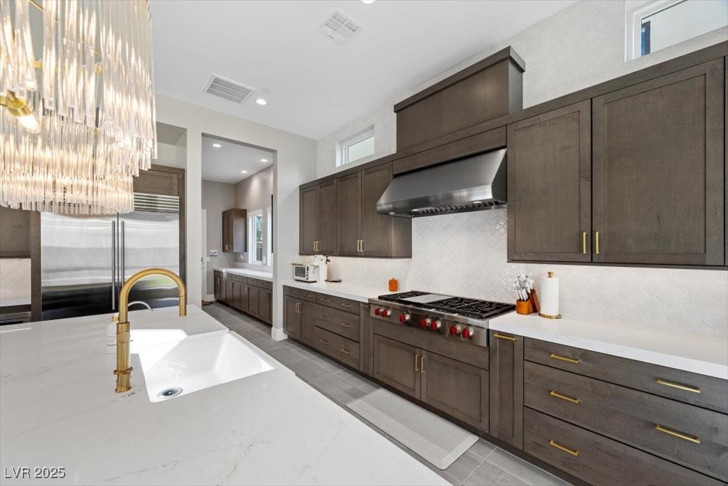 Modern kitchen with dark wood cabinetry, a large white island, and a professional gas range.