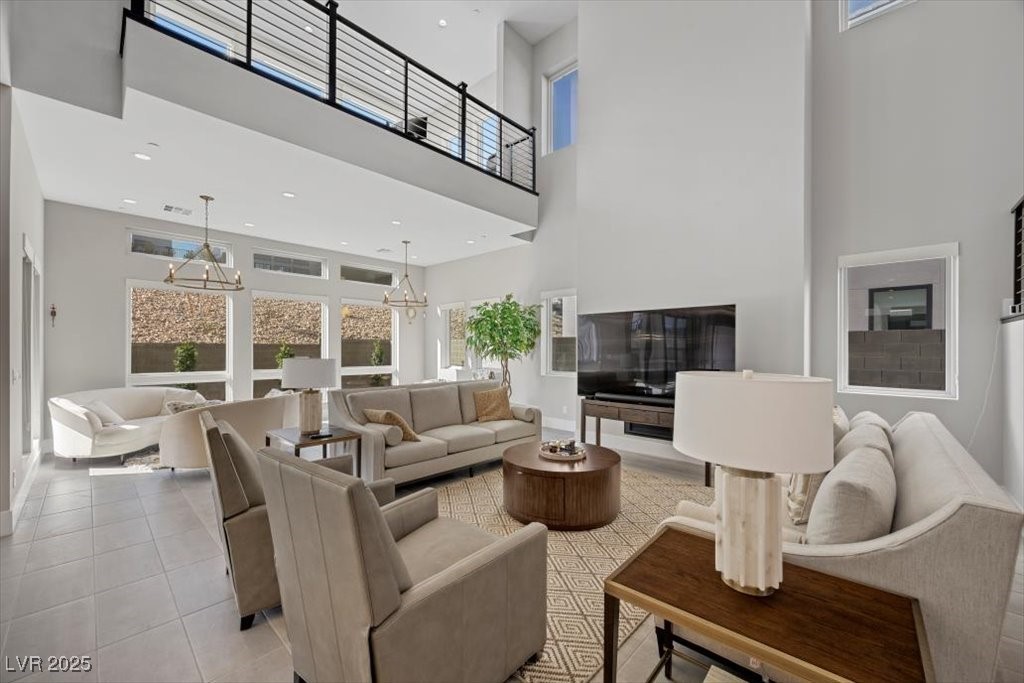Double-height living room with neutral seating, large windows, and an upstairs balcony.