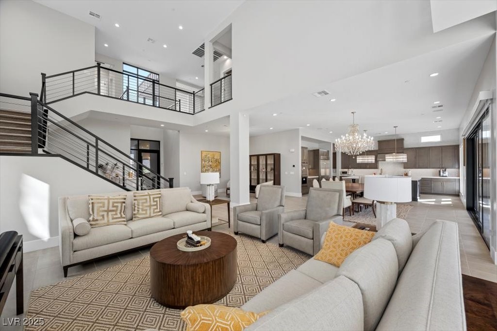 Open-plan living room and kitchen with a double-height ceiling, metal-railed staircase, and large island.