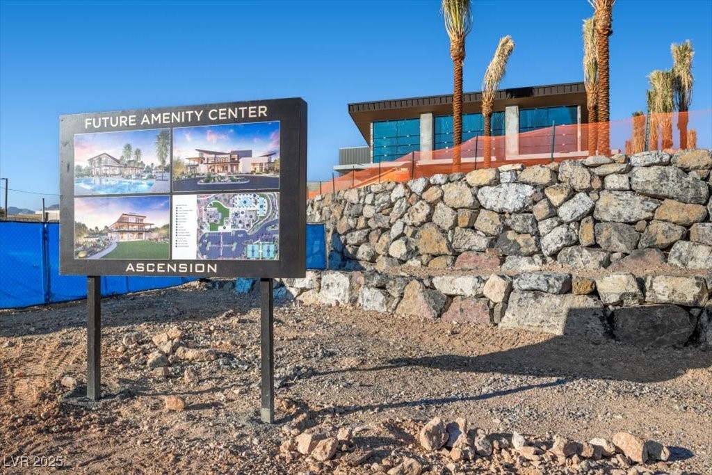 Future amenity center under construction behind a stone retaining wall, with an Ascension sign and palm trees.