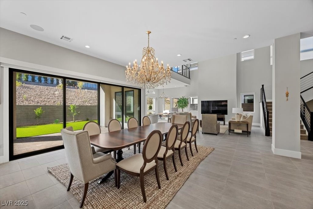 Open-plan dining room with a long table, crystal chandelier, and sliding glass doors to the yard.