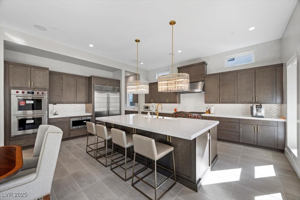 Modern kitchen with a large white island, dark cabinetry, and stainless steel appliances.