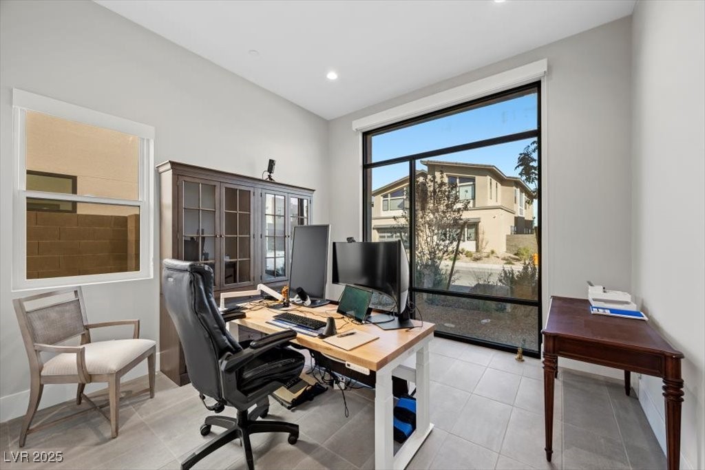 Home office with a computer workstation, glass-front cabinet, and large picture window.