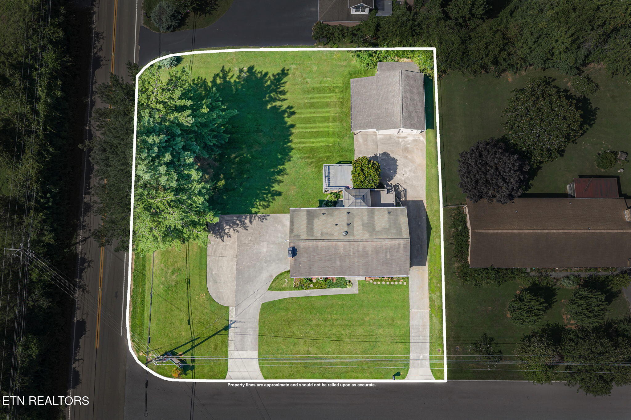 Aerial view of a home and its tree-lined lawn within outlined property boundaries.