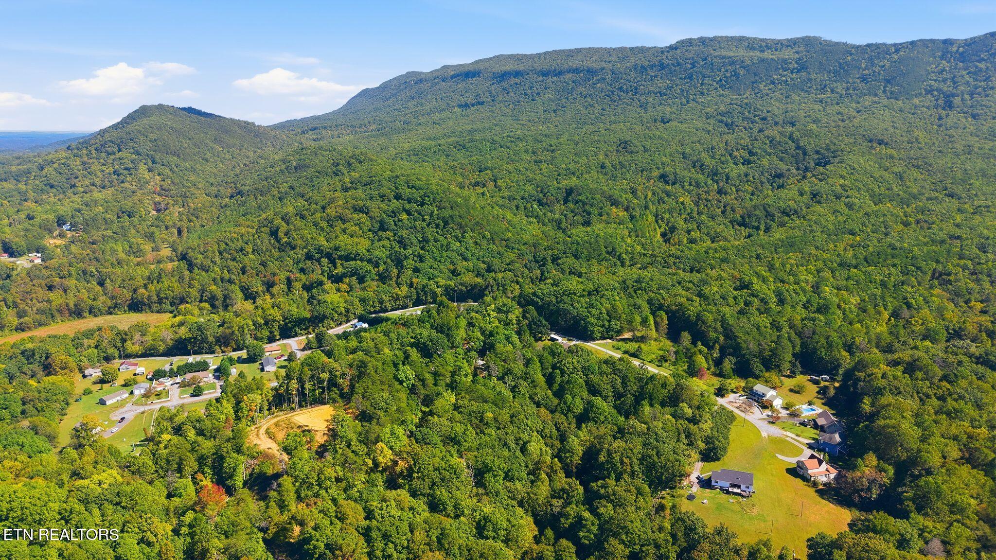 Aerial view of a wooded mountain ridge and scattered homes in a rural valley.