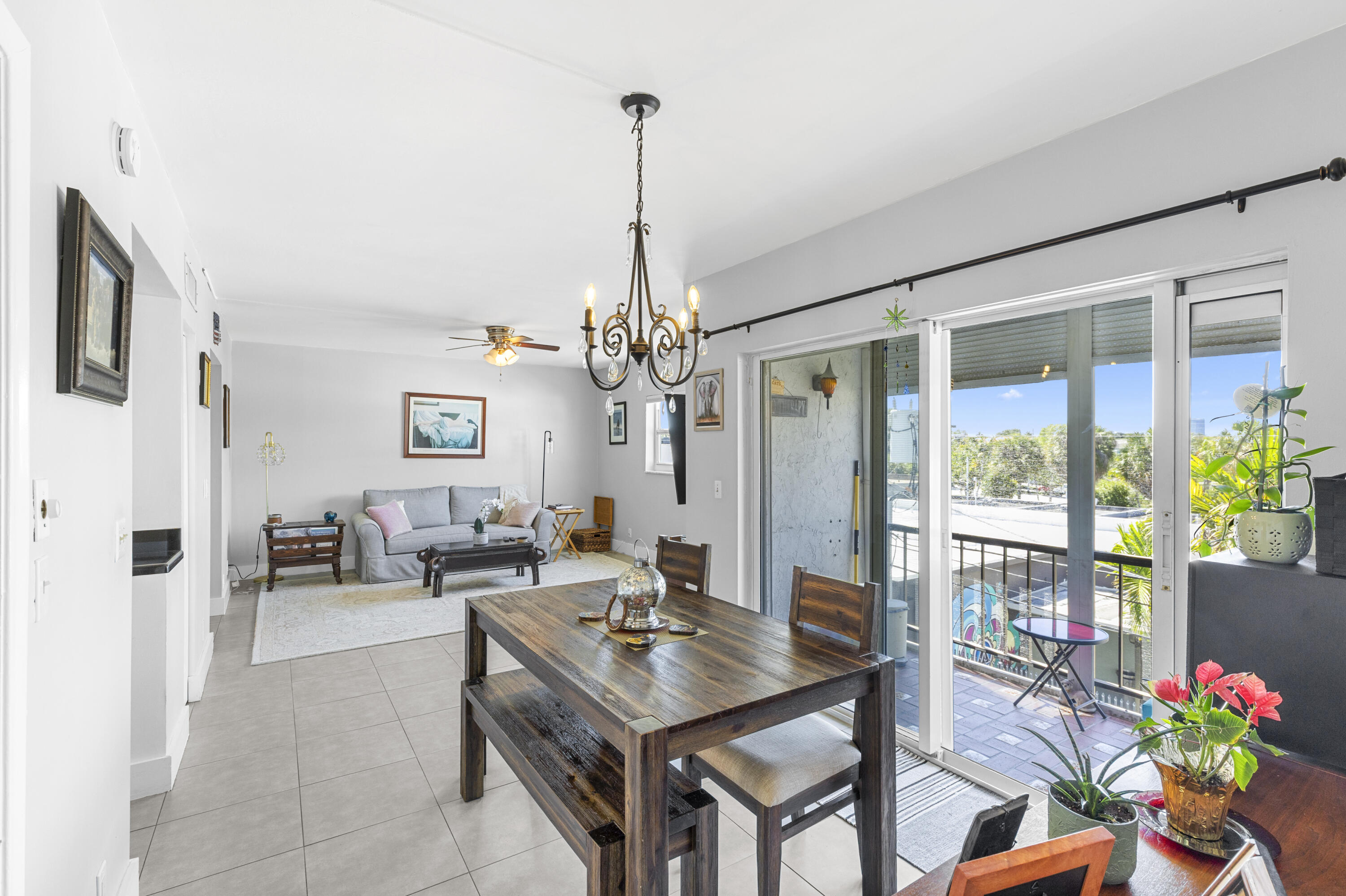 Furnished condo living and dining area with a dark wood table and sliding doors to a balcony.