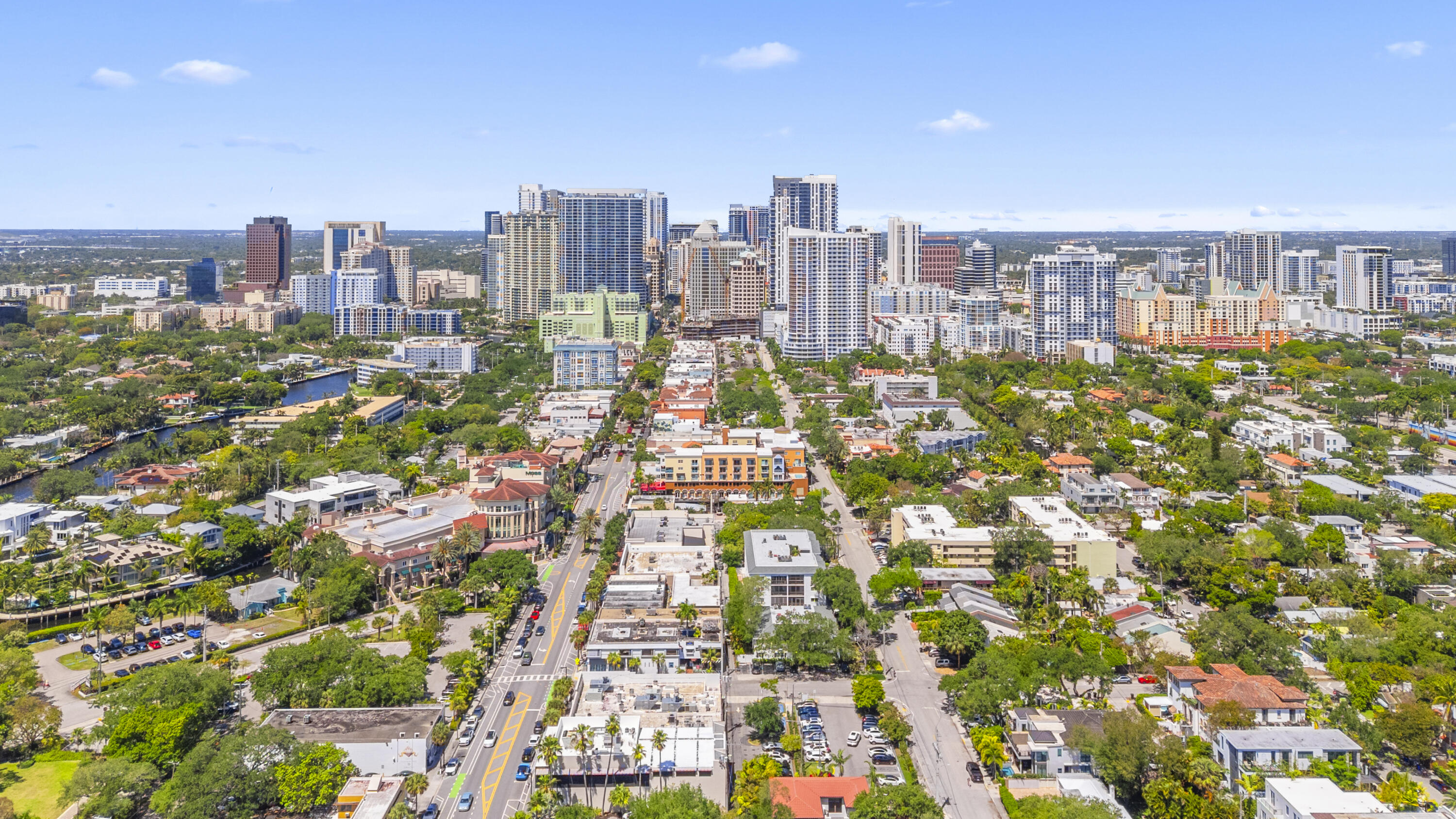 Aerial view of downtown Fort Lauderdale skyline, canal, and tree-lined neighborhood.