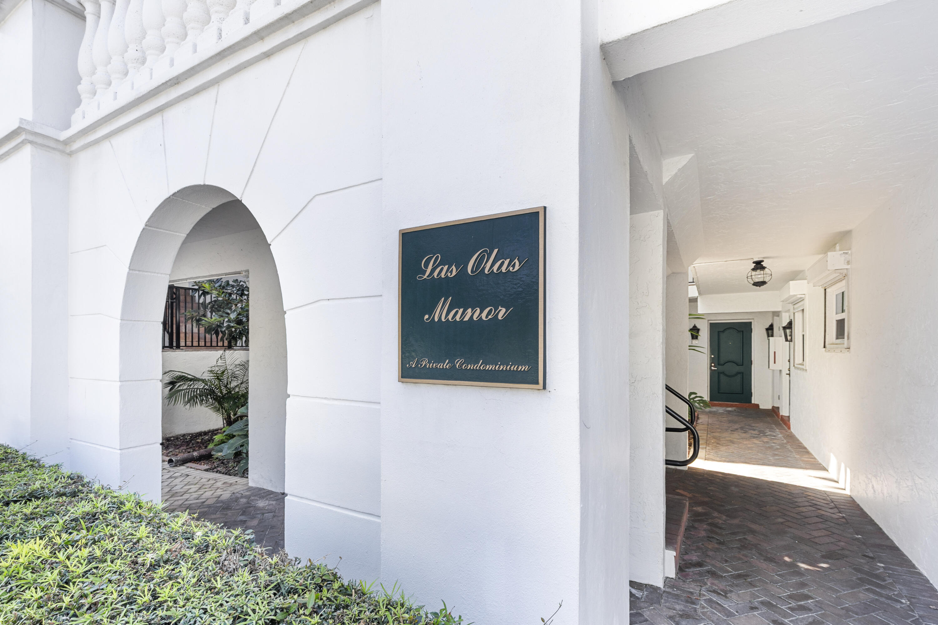 Las Olas Manor condominium entrance with an arched entry and brick-paved corridor.